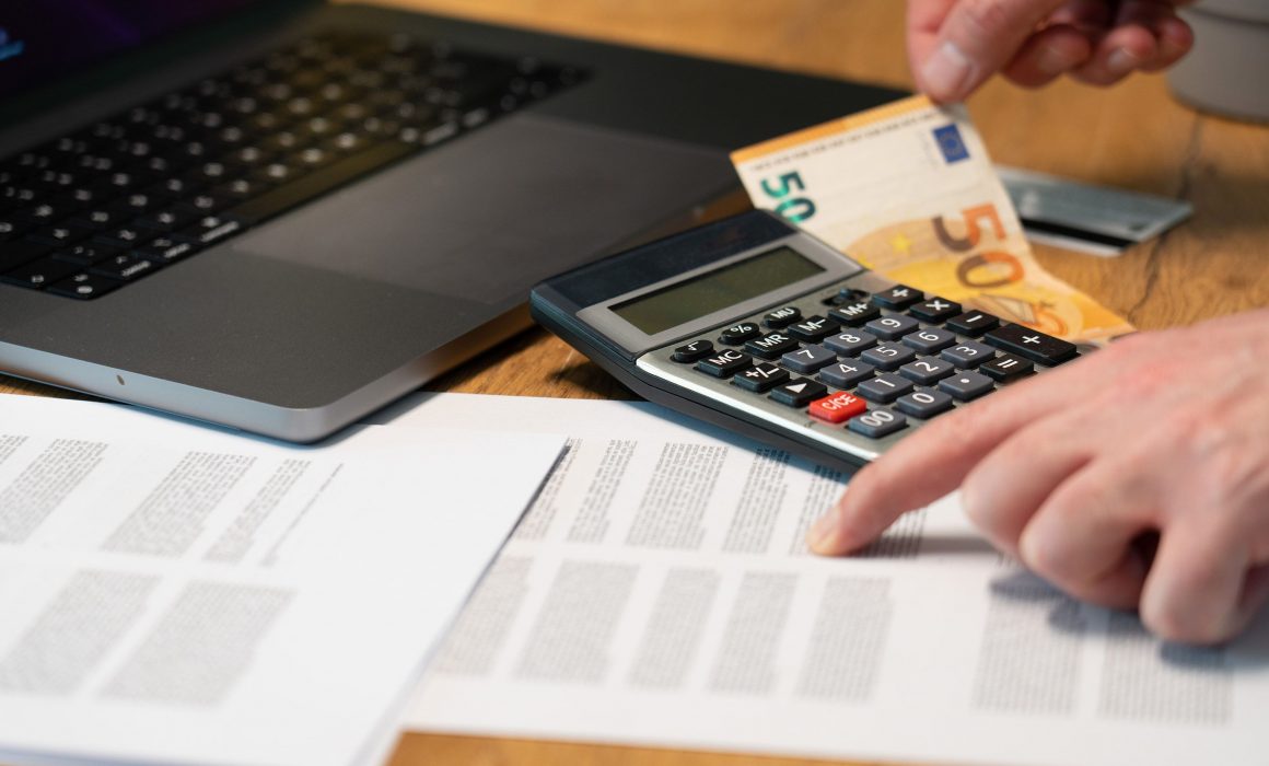 Un ordinateur, des feuilles de comptabilité, une calculatrice et un billet.